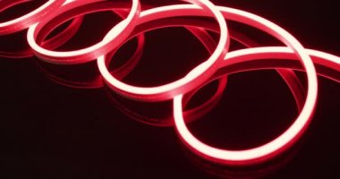 Kırmızı neon ışıklarının animasyonu siyah arkaplan üzerinde spiral oluşturur. Arkaplan, telif alanı ve renk kavramı.