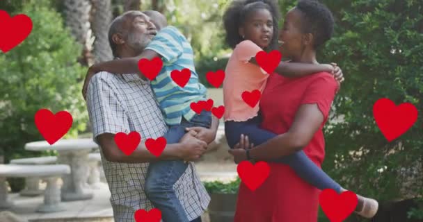 Анимация Сердец Над Счастливой Африканской Семьей Нескольких Поколений Обнимающейся Саду — стоковое видео