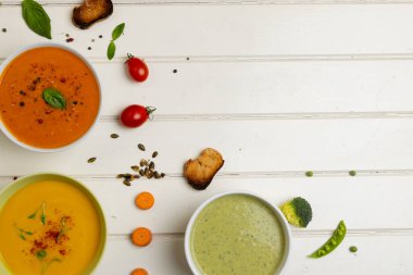 Beyaz ahşap üzerinde havuç, brokoli ve domates çorbasının fotokopi alanındaki yatay görüntüsü. Lezzetli ev yemekleri ve sağlıklı yemekler..
