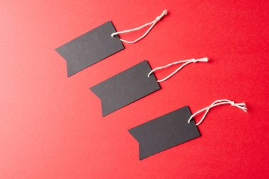 Kırmızı arkaplanda kopya alanı olan hediye etiketlerinin bileşimi. Perakende, alışveriş ve Kara Cuma konsepti.