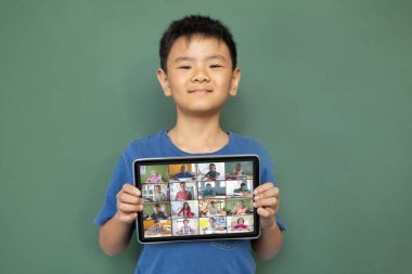 Çeşitli ilkokul öğrencileriyle video görüşmesi için elinde tablet olan gülümseyen Asyalı çocuk. iletişim teknolojisi ve çevrimiçi eğitim, dijital kompozit resim.