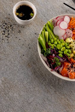 Gri arka planda soya sosu ve yemek çubuklarıyla Hawai poke kasesinin genel manzarası. Hawaii Lezzetli Taze Yemek ve Sağlıklı Yeme.