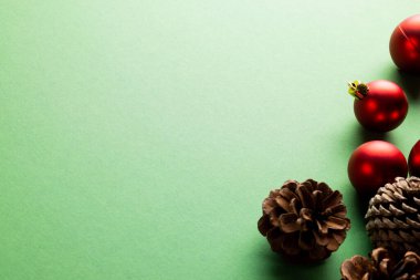 Çam kozalakları, takılar ve yeşil arka planda kopyalama alanı ile noel süslemesi. Noel, gelenek ve kutlama konsepti.