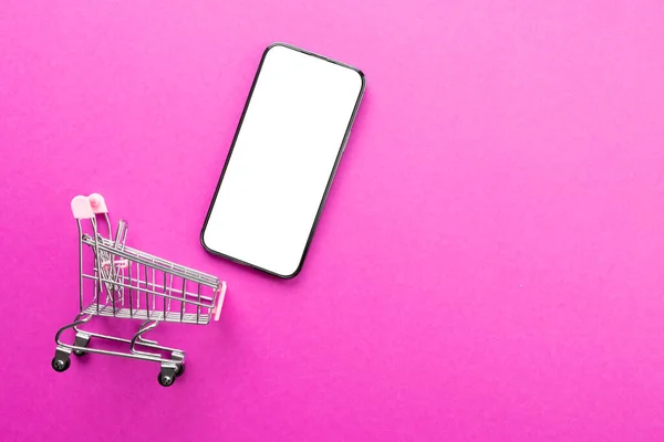 Zusammensetzung Von Warenkorb Und Smartphone Mit Kopierraum Auf Rosa Hintergrund — Stockfoto