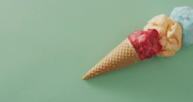 Yeşil yüzeyde duran dondurmalı koni videosu. Yemek, yemek, tatlı, mutfak ve yemek pişirme konsepti.