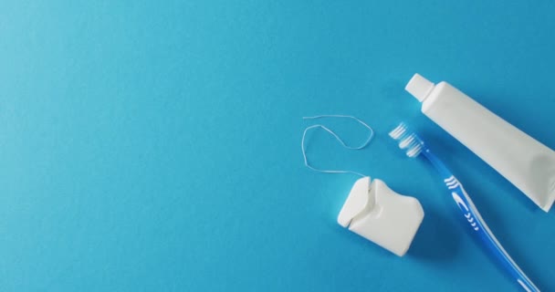 歯ブラシの近くのビデオ ペーストし 青の背景に花 生活習慣 コピースペースの概念 — ストック動画