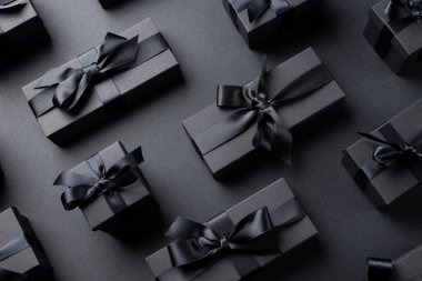 Gri arka planda siyah kurdeleli hediyelerin kompozisyonu. Perakende, alışveriş ve Kara Cuma konsepti.