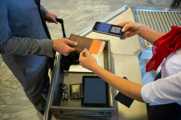 Man at airport showing documents and smartphone with covid 19 vaccine passport at check in. global covid 19 pandemic concept digitally generated video.