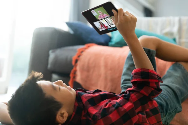 ビデオ通話にタブレットを使用してアジアの少年を笑顔 画面上の多様な小学校の生徒と 通信技術とオンライン教育デジタル複合画像 — ストック写真