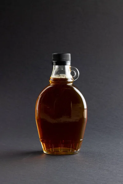 Вертикальне Зображення Скляної Пляшки Кленового Сиропу Темно Сірому Фоні Копіювальним — стокове фото