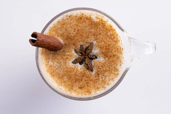 Image of glass of christmas milk with cinnamon stick and anise star and copy space on white. Christmas, tradition and celebration concept.