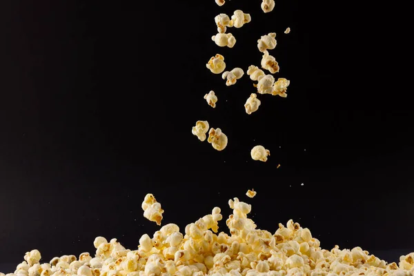 Image of pop corn spilled on black background. Food, snacks, cinema and american cuisine concept.