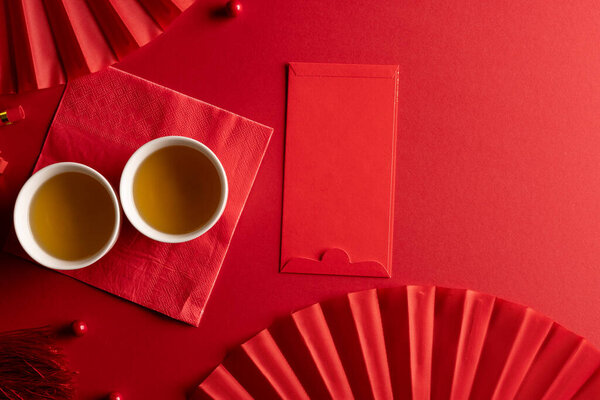 Composition of traditional chinese decorations and fans on red background. Chinese new year, tradition and celebration concept.
