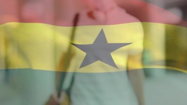 Caddede yüzü maskeli Latin bir adamın üzerinde sallanan Gana bayrağının animasyonu. covid 19 salgın konsepti boyunca dijital olarak üretilen küresel sağlık önlemleri.