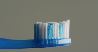 Gri arka planda diş fırçası ve yapıştırıcının yakın çekim videosu. Sağlık, stomatoloji ve kopyalama alanı kavramı.