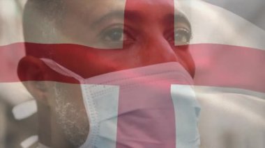 İngiliz bayrağının şehir caddesinde maskeli Afro-Amerikan bir adamın üzerinde sallanmasının animasyonu. covid 19 salgın konsepti boyunca dijital olarak üretilen küresel sağlık önlemleri.