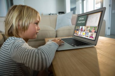 Beyaz çocuk ekranda çeşitli ilköğretim öğrencileri gülümserken görüntülü konuşma için laptop kullanıyor. iletişim teknolojisi ve çevrimiçi eğitim, dijital kompozit resim.