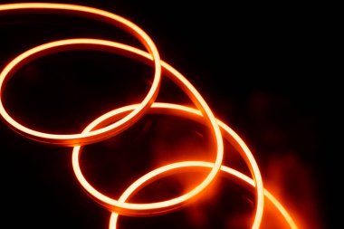 Fotokopi uzayı ile siyah arkaplan üzerinde parlak turuncu ışıklı çubuklar. Işık ve renk kavramı.