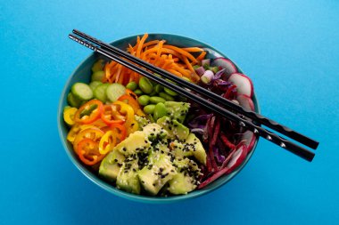 Havai poke kasesinin mavi arka planında yemek çubukları var. Hawaii Lezzetli Taze Yemek ve Sağlıklı Yeme.