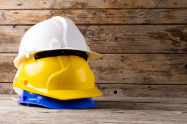 Ahşap yüzeyde duran bir yığın kask resmi. Çalışma, koruma, güvenlik ve yapı ekipmanları kavramı.