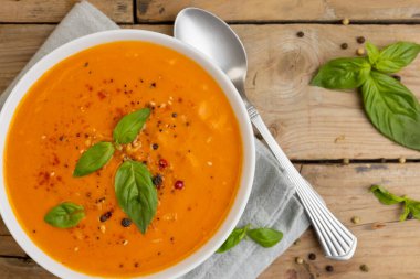 Fesleğen yapraklı bir kase domates çorbası, tahta üzerinde kaşık ve peçete, kopyalama alanı. Lezzetli ev yemekleri ve sağlıklı yemekler..