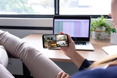 Beyaz kadın elinde akıllı telefon ile evdeki güvenlik kameralarını ekranda görüyor. güvenlik, güvenlik, izleme ve dijital arayüz.