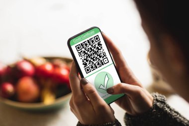 Evde elinde kovanlı 19 aşılı pasaportlu akıllı telefon tutan bir kadın var. küresel covid 19 salgın konsepti dijital olarak oluşturulmuş video.