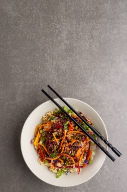 Gri arka planda fotokopi alanı olan Asyalı tava kızartma ve yemek çubuklarının genel görünümü. Asyalı lezzetli ev yemekleri ve sağlıklı yiyecekler..