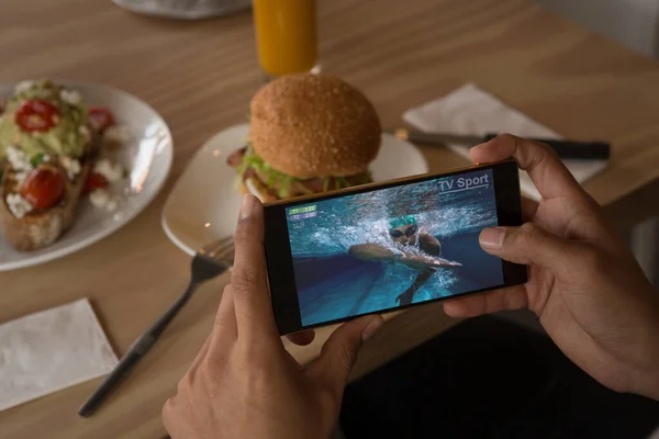 Händerna Afrikansk Amerikansk Man Restaurang Tittar Simtävling Smartphone Sport Konkurrens — Stockfoto