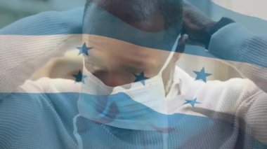 Honduras bayrağının şehir caddesinde maskeli Afro-Amerikan bir adamın üzerinde dalgalanması. covid 19 salgın konsepti boyunca dijital olarak üretilen küresel sağlık önlemleri.