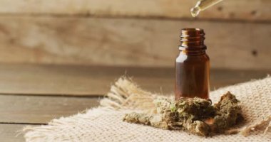 Marihuana tomurcukları ve ahşap arka planda bir şişe cbd özütü videosu. Sağlık tedavileri ve tıbbi yardımlar için Cbd, cannabidiol özü ve esrar.