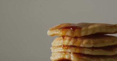 Akçaağaç şurubunun gri arka planda kreplere döküldüğü bir video. Amerikan mutfağı, yemek, yemek ve yemek konsepti.