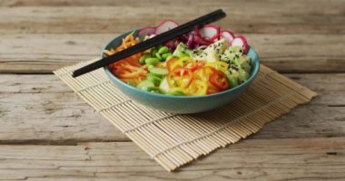 Ahşap zemin üzerinde yemek çubukları olan bir kase pirinç ve sebze kompozisyonu. Yiyecek, içecek ve renk konsepti.