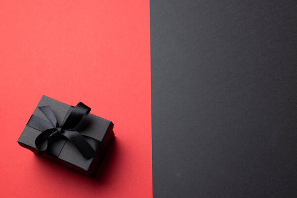Composition of present with black ribbon on gray and pink background. Retail, shopping and black friday concept.