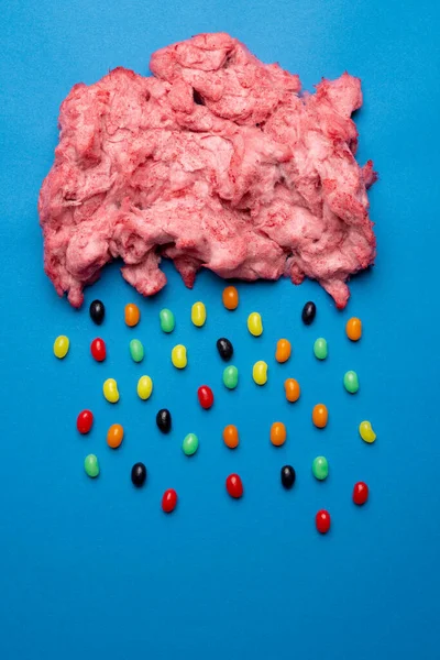 Ev yapımı pembe şeker diş ipinin dikey görüntüsü. Fotokopi alanı ile mavi üzerine jelibon yağıyor. Lezzetli ev yapımı tatlı yiyecekler..