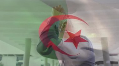 Cezayir bayrağının şehir caddesinde yüz maskesi takan beyaz adamın üzerinde dalgalanması. covid 19 salgın konsepti boyunca dijital olarak üretilen küresel sağlık önlemleri.