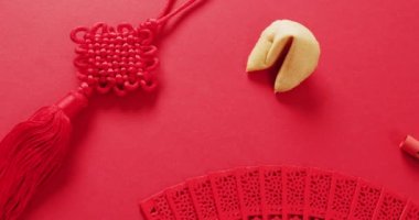 Kırmızı arka planda Çin yelpazesinin ve dekorasyonların yakın çekim videosu. Çin yeni yılı, gelenek ve kutlama konsepti.