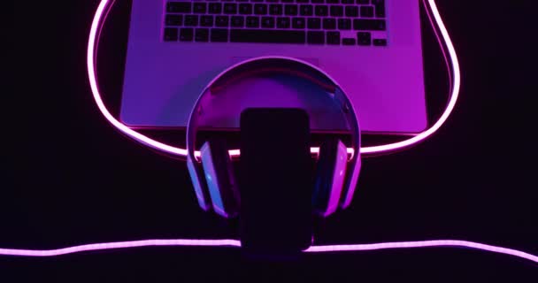 Zusammensetzung Aus Laptop Kopfhörer Und Smartphone Mit Rosa Neonlichtern Auf — Stockvideo