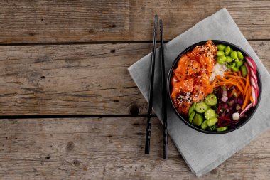 Havai Poke Bowl 'un yemek çubukları ve ahşap arka planda fotokopi alanı manzarası. Hawaii Lezzetli Taze Yemek ve Sağlıklı Yeme.