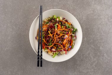 Gri arka planda Asyalı tava kızartması ve çubuk yemek manzarası. Asyalı lezzetli ev yemekleri ve sağlıklı yiyecekler..