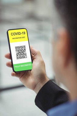 Elinde kovanlı 19 aşılı pasaportlu akıllı telefon tutan adam. küresel covid 19 salgın konsepti dijital olarak oluşturulmuş video.