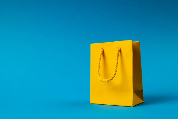 青い背景に黄色の紙のショッピングバッグの組成 ショッピング 黒の金曜日のコンセプト — ストック写真