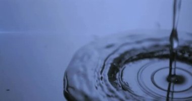 Parlayan ışıkla mavi suya düşen suyun animasyonu. Hareket ve ışık konsepti dijital olarak oluşturulmuş video.