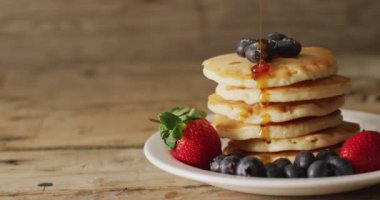 Ahşap arka planda meyveli kreplere akan akçaağaç şurubu videosu. Amerikan mutfağı, yemek, yemek ve yemek konsepti.