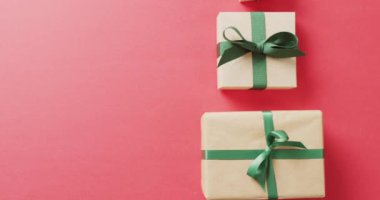 Yılbaşı hediyelerinin ve kurdelenin Noel ağacı oluşturduğu ve pembe arka planda fotokopi alanı oluşturduğu bir video. Noel, gelenek ve kutlama konsepti.