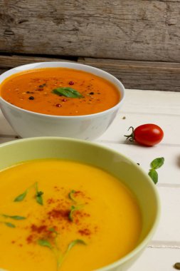 Beyaz ahşap üzerinde havuç ve domates çorbasının fotokopi alanı olan dikey görüntüsü. Lezzetli ev yemekleri ve sağlıklı yemekler..