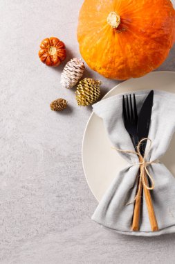 Tabak manzarası, çatal bıçak, peçete, balkabağı, çam kozalağı ve gri üzerine kopyalama alanı. Şükran Günü, Sonbahar, Sonbahar, Amerikan geleneği ve kutlama konsepti.