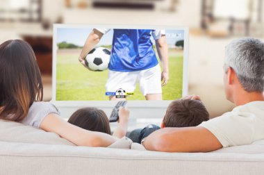 Futbol oyuncular tacakling için sahada top karşı birlikte televizyon izlerken kanepede oturan aile