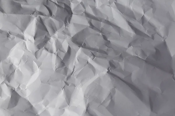 Close up of light and shadow on creases in sheet of white paper. monochrome light and texture, abstract background image.