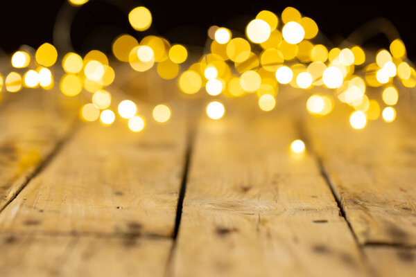 Image of christmas out of focus fairy lights and copy space on wooden background. Christmas, tradition and celebration concept.